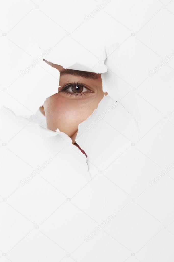 woman looking through ripped paper