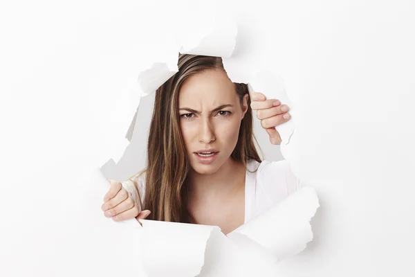 Mulher olhando através de papel rasgado — Fotografia de Stock