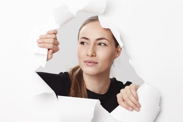 Vrouw op zoek via gescheurd papier — Stockfoto