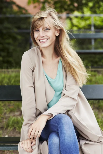 Красива жінка посміхається на лавці парку — стокове фото