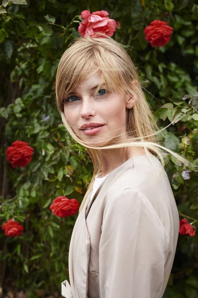 Mulher na frente de rosas vermelhas arbusto — Fotografia de Stock