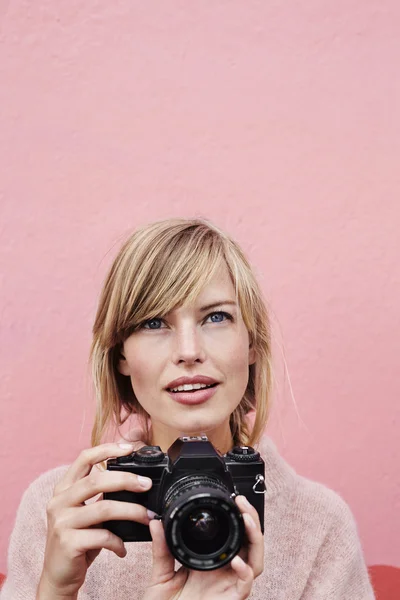 Woman looking up and holding camera — Stock Photo, Image
