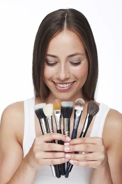 Mujer mirando pinceles de maquillaje — Foto de Stock