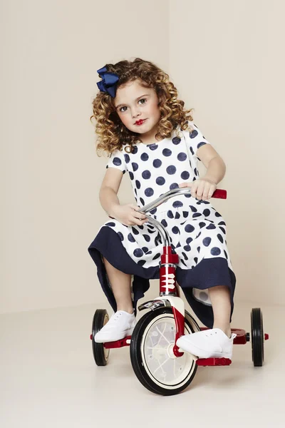 Ragazza in abito macchiato sul triciclo — Foto Stock