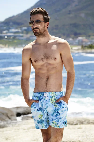 Young man in shorts on beach — Stock Photo, Image