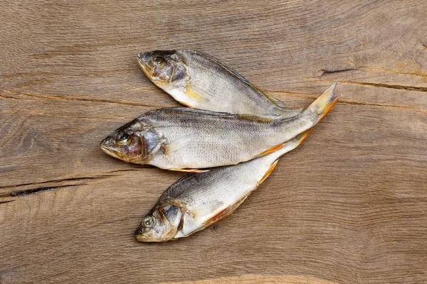 Tre pesci secchi su fondo di legno . — Foto Stock