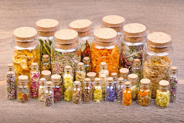 Verschillende soorten thee en healing kruiden in glazen flessen op helder — Stockfoto