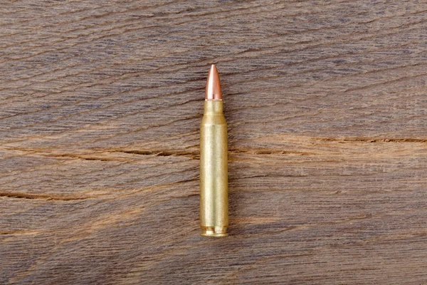 Rifle bulet on old wood desk. — Stock Fotó