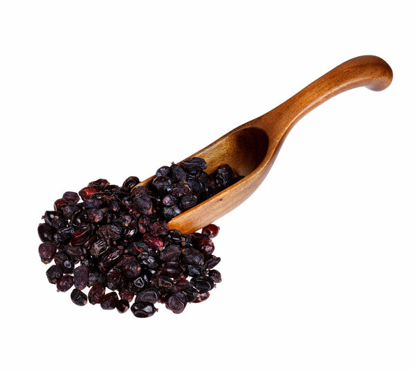 Black dry barberry in the wooden spoon, isolated on white backgr