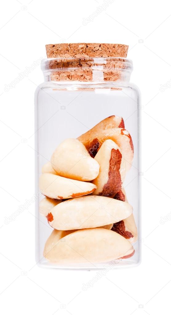 Brazil nuts in a glass bottle with cork stopper, isolated on whi
