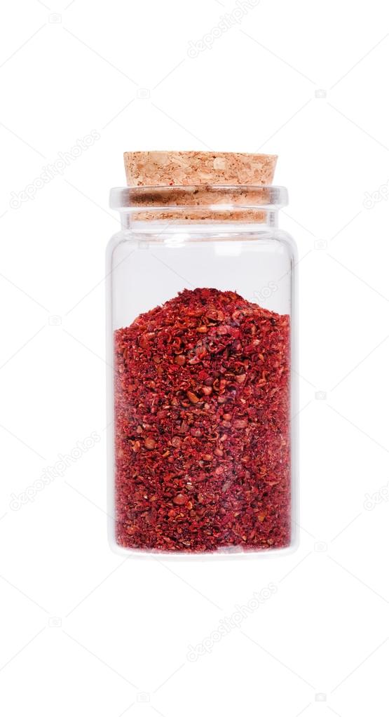 Sumac in a glass bottle with cork stopper, isolated on white.
