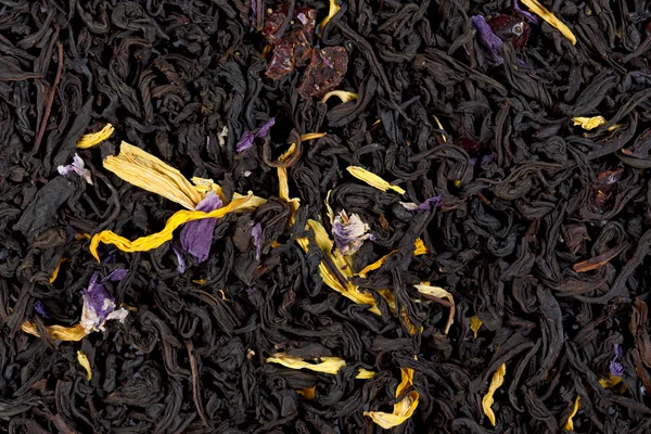 Aromatischer schwarzer Tee mit Sonnenblumen- und Kornblumenblütenblättern — Stockfoto