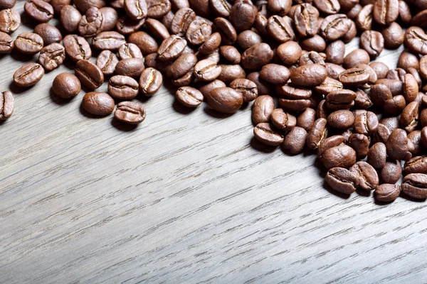 Kávová zrna na hnědé dřevěné pozadí. — Stock fotografie