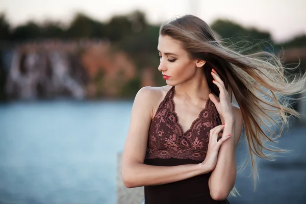 Mulher na moda jovem bonita posando em vestido na costa do rio à noite após o pôr do sol. Estilo Vogue. Fundo urbano — Fotografia de Stock