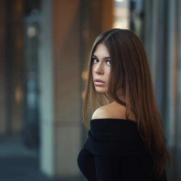 Hermosa mujer joven morena en bonito vestido negro. Posando sobre fondo urbano. Foto de moda —  Fotos de Stock