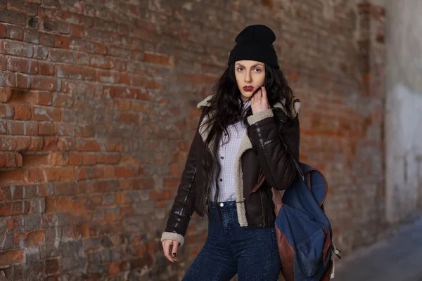 Outdoor lifestyle portrait of pretty young girl, wearing hipster swag grunge style on urban background. Wearing hat and jeans with backpack. Spring fashion woman. Toned style instagram filters. — Stockfoto