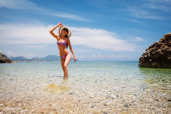 Bikini, yaratıcı şapka ve deniz arka planda güneş gözlüğü güzel kadın seksi arka. Kemer yakınlarındaki deniz kıyısı, Antalya, Türkiye. — Stok fotoğraf