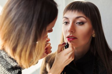 Model dudaklarda fırça ile ruj uygulayan makyaj sanatçısı