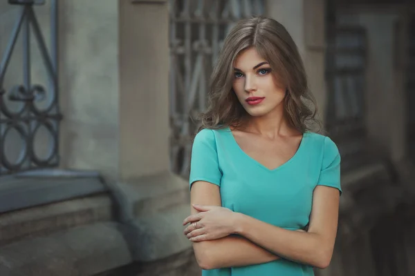 Retrato de estilo de vida al aire libre de una chica joven y bonita, vestida de azul sobre fondo urbano. Imagen tonificada de color creativo . —  Fotos de Stock