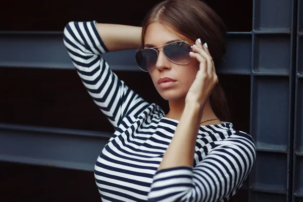 Beautiful brunette young woman in nice striped dress, sunglasses. Posing on urban background. Fashion Photo — Stock Photo, Image