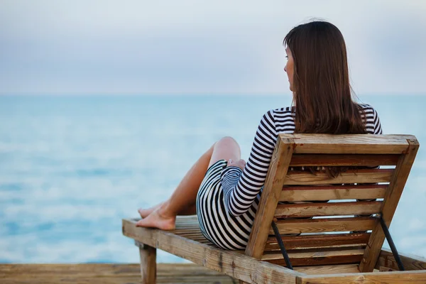 Outdoor portrait of beautiful young woman relaxing at the seacoast at the evening Stock Picture