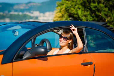 Güzel genç kadın uzun saçlı oturan ve Akdeniz sahilinde turuncu Cabriolet gülümseyen 