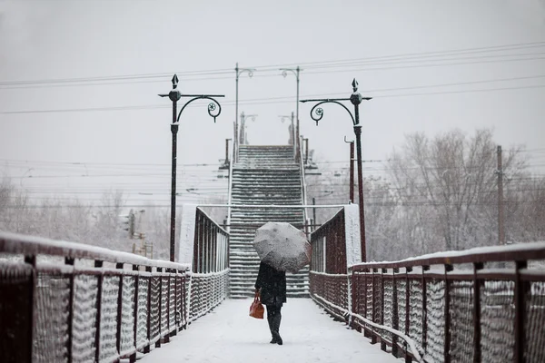 Une jeune femme traverse le pont en chute de neige — Photo