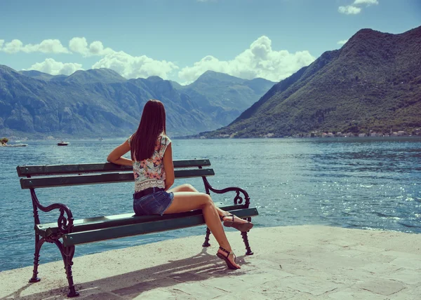Beautiful young woman looking and waiting at the seacoast. Sunny day. Montenegro, Europe. Retro style toning image. — Stock Photo, Image