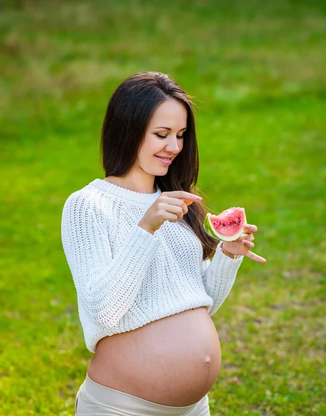 Ung, gravid kvinne som slapper av i parken utendørs, frisk graviditet – stockfoto