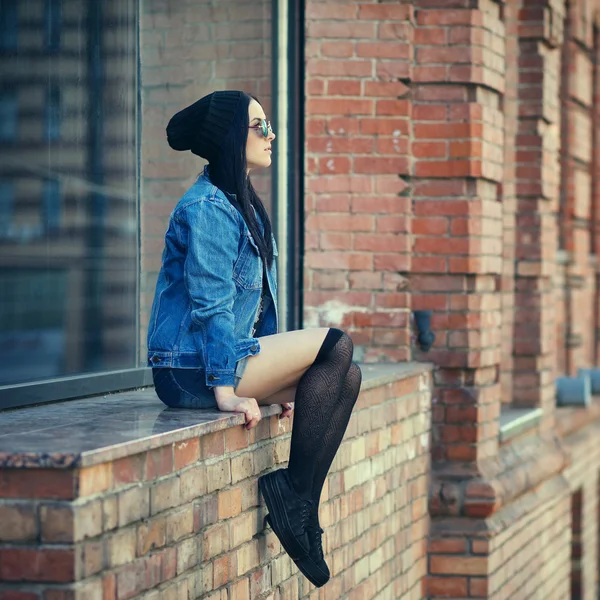 Estilo de vida ao ar livre retrato de muito jovem sentada menina, vestindo em estilo de grunge hipster swag em fundo urbano. Retro vintage tonificado imagem, simulação de filme . — Fotografia de Stock