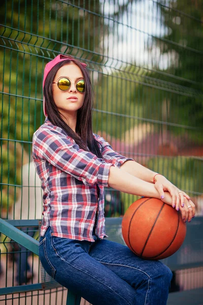 Outdoor lifestyle portret van mooie jonge vergadering meisje, dragen in hipster swag grunge stijl met basketbal in stedelijke achtergrond. Retro vintage afgezwakt beeld, filmsimulatie. — Stockfoto