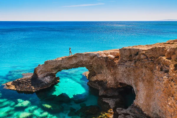 Женщина на красивой природной скальной арке недалеко от Айя-Напы, Каво Греко и Протараса на острове Кипр, Средиземное море. Легендарные любители мостов. Удивительное сине-зеленое море и солнечный день . — стоковое фото