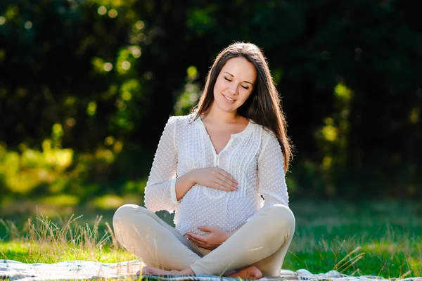 Ung, gravid kvinne som slapper av i parken utendørs, frisk graviditet – stockfoto