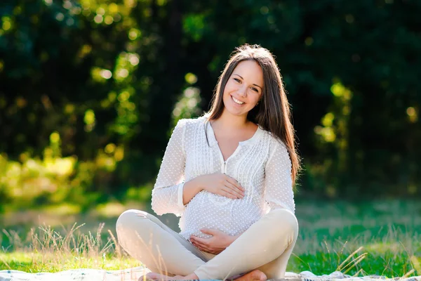 Young pregnant woman relaxing in park outdoors, healthy pregnancy — Stock Photo, Image