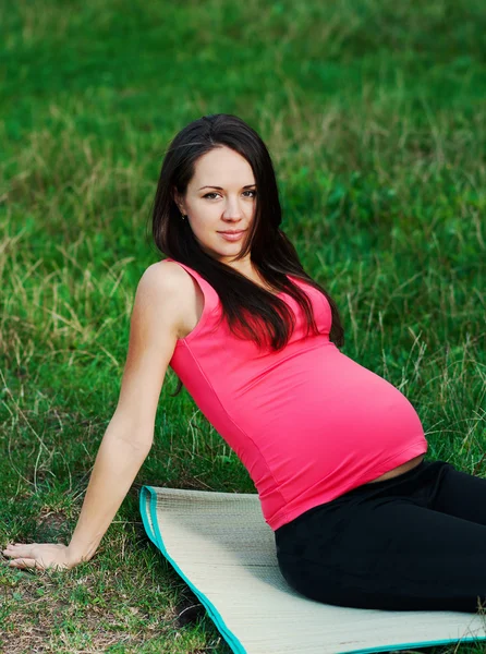 Mujer embarazada joven relajándose en el parque al aire libre, embarazo saludable —  Fotos de Stock