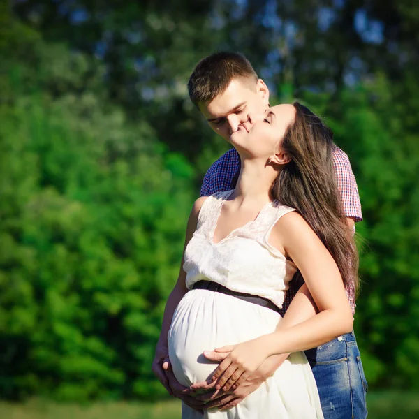 Happy and young pregnant couple hugging in nature Royalty Free Stock Photos