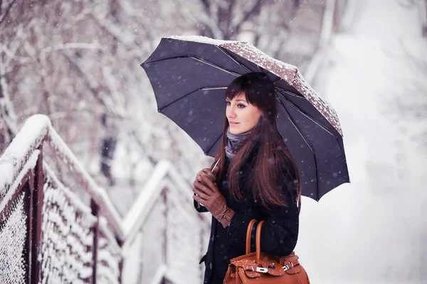 Hermosa mujer joven con paraguas en la imagen tonificada nevada — Foto de Stock