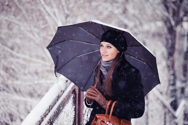 Belle jeune femme avec parapluie dans l'image tonique de chutes de neige — Photo