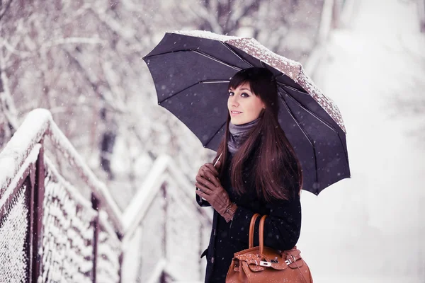 Красивая молодая женщина с зонтиком в тонусе снегопада — стоковое фото