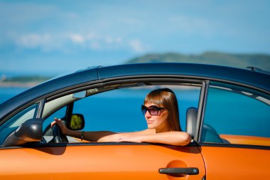 Güzel genç kadın uzun saçlı turuncu Cabriolet Akdeniz sahilinde oturan 