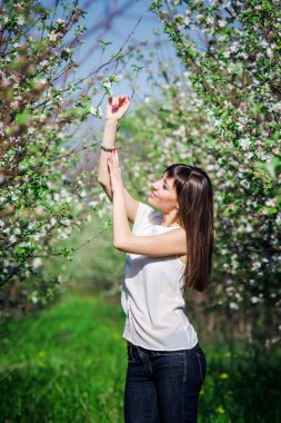 Çiçeği elma ağacı yeşil çim ile bahar bahçe beyaz çiçeklerle yakınındaki güzel gülümseyen kız