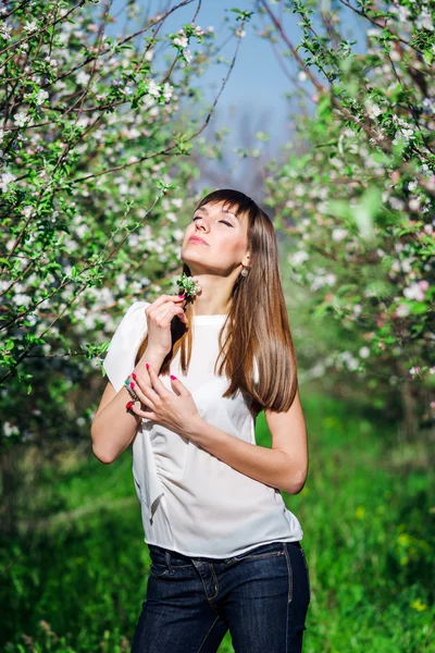 Hermosa chica sonriente cerca del manzano con flores blancas en el jardín de primavera con hierba verdeHermosa chica sonriente cerca del manzano con flores blancas en el jardín de primavera con hierba verde . — Foto de Stock