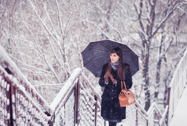Красивая молодая женщина с зонтиком в тонусе снегопада — стоковое фото