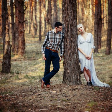 Genç çift çam ormanı içinde açık hava yaşam tarzı portresi. Güneşli sıcak hava. Retro vintage tonlu görüntü, film simülasyon.