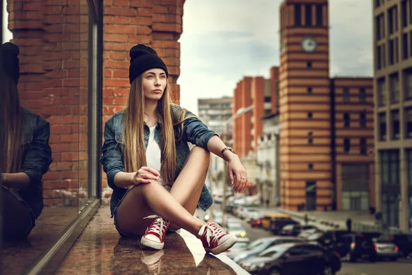 Estilo de vida ao ar livre retrato de muito jovem sentada menina, vestindo em hipster swag grunge estilo de fundo urbano. Retro vintage tonificado imagem, simulação de filme . — Fotografia de Stock