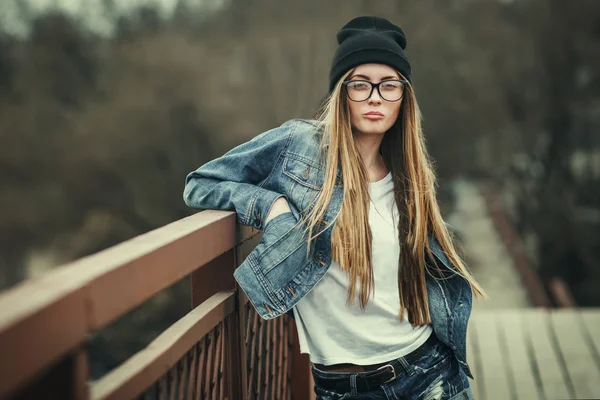 Outdoor-Lifestyle-Porträt eines hübschen jungen Mädchens, das im Hipster-Swag-Grunge-Stil urbanen Hintergrund trägt. Retro Vintage getöntes Image, Filmsimulation. — Stockfoto