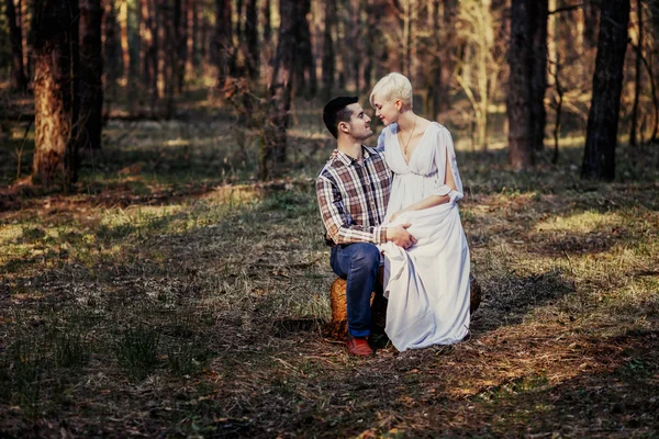 Outdoor lifestyle portrait of young couple hugging in pine forest. Sunny warm weather. Retro vintage toned image, film simulation.