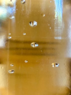 Yüzeyinde küçük damlacıklar olan bir bardak sıvı. Damlacıklar camın her tarafına dağılmış bulanık ve bulanık bir etki yaratıyor. Hareket ve akıcılık kavramı