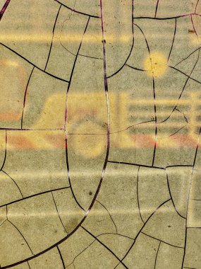 Görüntü çatlamış ve kırılmış bir yüzeye yakın plan, muhtemelen bir duvar ya da bir çömlek parçası. Çatlaklar ve çentikler yüzeyi yıpranmış ve yıpranmış gösteriyor.