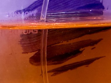 Üzerinde fırça izi olan bir bardak sıvı. Fırça izi camın ortasında ve koyu renkli.